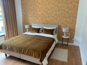 a bedroom with a large bed with a gold wall at Coco’s place in Antwerp