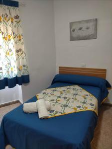 1 dormitorio con cama con sábanas azules y ventana en Casa joselito, en Casas del Cerro