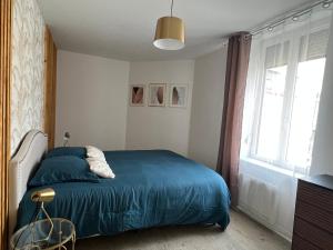 sypialnia z niebieskim łóżkiem i oknem w obiekcie Le Saphir de Calais - Chic et élegant w Calais