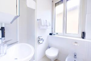 a white bathroom with a toilet and a sink at Hotel San Carlo in Lugano