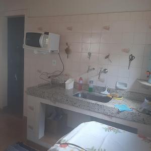 een keuken met een wastafel en een magnetron bij Casa para Aluguel de Temporada - Carrancas MG in Carrancas