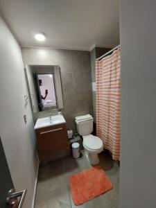 y baño con aseo, lavabo y espejo. en Hermoso departamento nuevo amoblado en Arica