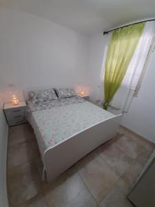 a white bedroom with a bed and a window at Casa vacanze Leonardo in Peschici