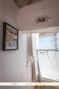 a bathroom with a tub and a shower with a sign on the wall at Le Nid des Anges, votre studio à la campagne. in Saint-Laurent-du-Plan