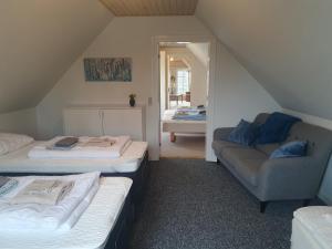 um quarto no sótão com 2 camas e um sofá em Damsbo hytten em Brenderup