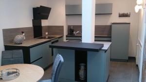 - une cuisine avec des placards bleus, un évier et une table dans l'établissement Le 4, à Bayeux