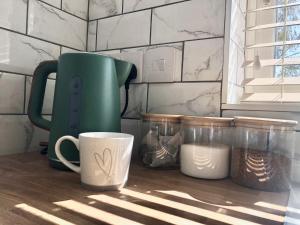 a kitchen counter with a green kettle and a cup at The Heathers, Scratby in Scratby