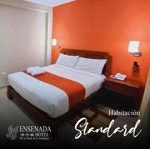 a bedroom with a large bed with an orange wall at Ensenada Hotel in San Juan de Marcona