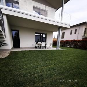 ein weißes Haus mit Rasen davor in der Unterkunft Villa Oliveto 24 in Bardolino