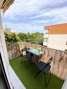 een patio met 2 stoelen en een tafel op het gras bij Grand studio cosy à 300m de la mer avec parking in Canet-en-Roussillon
