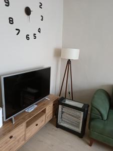 a living room with a flat screen tv and a chair at daily rental apartment 5 minutes to the airport in Pazar
