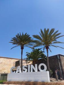 a sign in front of a building with palm trees at Villa Katerina in Caleta De Fuste