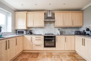 a kitchen with wooden cabinets and a stove top oven at Bulkington Lodge Coventry - Affordable Cosy Double & En-Suite Rooms in Bulkington