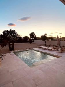 a swimming pool with lounge chairs and a sunset at Villa moderne entre centre ville et nature in Nîmes