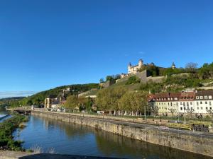 une rivière avec un château au sommet d'une colline dans l'établissement DachtRaum Waldner, à Wurtzbourg