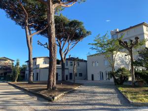 a row of trees in front of a white building at RE Versiliana Junior-House in Marina di Pietrasanta