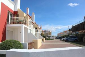 un edificio blanco con un aparcamiento con coches aparcados en Carlota House - Baleal, en Baleal