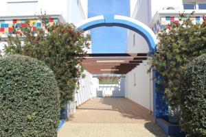 un pasillo con un edificio azul y blanco con arbustos en Carlota House - Baleal, en Baleal