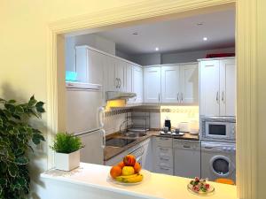 a kitchen with white cabinets and a plate of fruit on a counter at Dream Apartment in Mijas Golf Limonar in Mijas Costa +27 photos