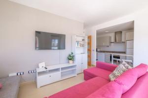 un salon avec un canapé rose et une cuisine dans l'établissement Apartamento GELUM Delta del Ebro, à Sant Jaume d'Enveja