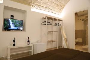 - une chambre avec un lit et une télévision murale dans l'établissement Al Guiscardo 8, à Bari
