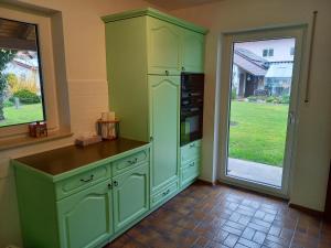 a kitchen with green cabinets and a sliding glass door at Ferienwohnung Riposo in Meersburg +6 photos