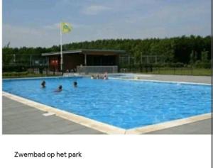 a large swimming pool with people in the water at Gastehuisie Goedemoed in Zeewolde