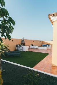 patio z zieloną trawą na boku domu w obiekcie Moderne villa met verwarmd zwembad in Corralejo w Corralejo