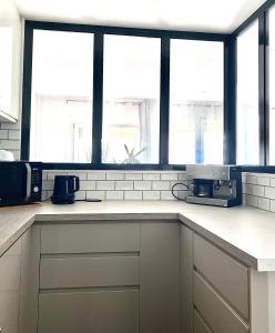 eine Küche mit weißen Arbeitsplatten und Fenstern in der Unterkunft Bel appartement complet: in Villetaneuse