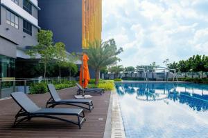 een zwembad met stoelen en een parasol naast een gebouw bij Elegant 3BR+3BTH 1min Linked MRT Apek Hill网红名宿3房3浴 in Kuala Lumpur