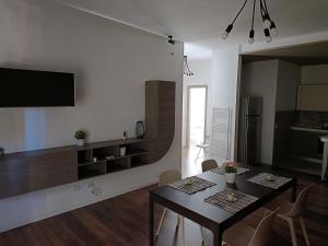 un soggiorno con tavolo, sedie e TV di Suite Bosco a Cisternino