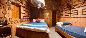 a bedroom with two beds in a room with wooden walls at Little Yen's Homestay in Mèo Vạc