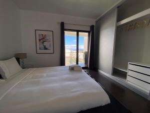 una camera da letto con un grande letto bianco e una finestra di Villa Madeira island a Caniço
