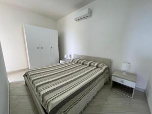 1 dormitorio con 1 cama y armario blanco en Le Verande di Isola Rossa, en Isola Rossa