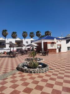 un patio con mesas, sillas y sombrillas en Casa Lila Montecastillo J9, en Caleta de Fuste 35 fotos más
