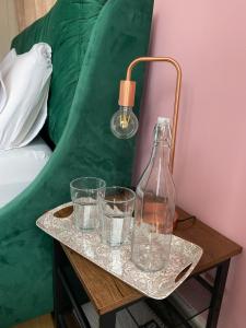 a tray with glasses and a bottle on a table next to a bed at The Lily Pad in Corfe Mullen