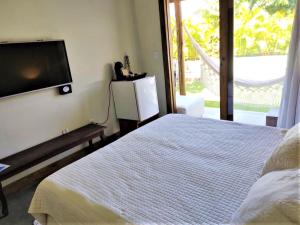 a bedroom with a bed and a flat screen tv at Pé na Areia - Pousada in Barra Grande