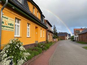 um arco-íris no céu atrás de uma casa amarela em Hotel Nordic Spreewald em Lübbenau