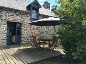 a table and chairs with an umbrella on a deck at Maisonnette au pied du Mont Dol in Mont-Dol