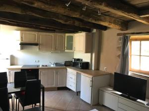 a kitchen with white cabinets and a table and chairs at Maisonnette au pied du Mont Dol in Mont-Dol