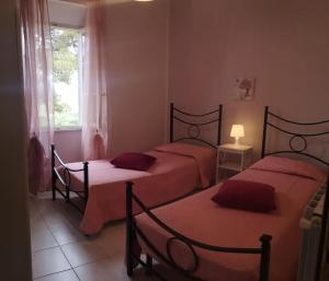una camera con due letti con lenzuola rosse e una finestra di La casa dei nonni a Capoliveri