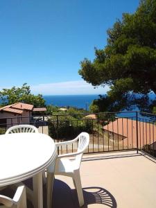 una mesa blanca y sillas en un balcón con vistas al océano en La casa dei nonni, en Capoliveri