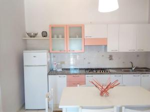 a kitchen with a white refrigerator and a white table at La casa dei nonni in Capoliveri