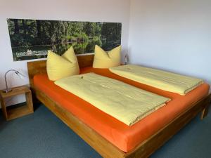 2 Betten mit gelber und orangefarbener Bettwäsche in einem Zimmer in der Unterkunft Hotel Nordic Spreewald in Lübbenau