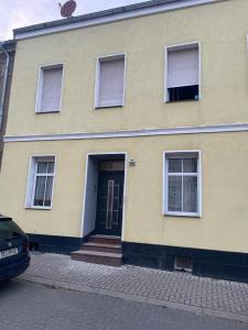 a yellow house with a blue door and windows at Pension Helga in Dessau