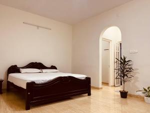 1 dormitorio con 1 cama grande y puerta abovedada en Nilgiri Comfort Stay, en Coonoor