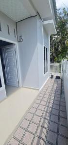 Casa blanca con puerta y suelo de baldosa en HOMESTAY PANDAN, en Halangan