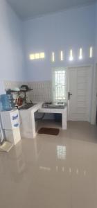 a white kitchen with a table and a door at HOMESTAY PANDAN in Halangan