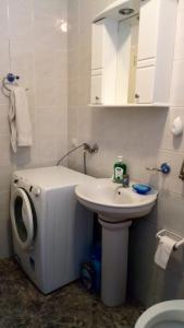 a white bathroom with a sink and a washing machine at Apartments Vozdovac in Belgrade