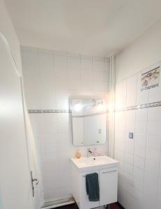 a white bathroom with a sink and a mirror at Bel appartement entre Disney Land et Paris in Chelles